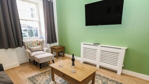 Een woonkamer met een bank, een salontafel, een televisie en een radiator.