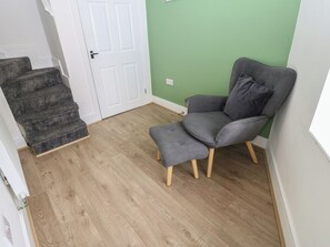 Ein Zimmer mit grauem Sessel, Holzboden, weißer Tür und grüner Wand.