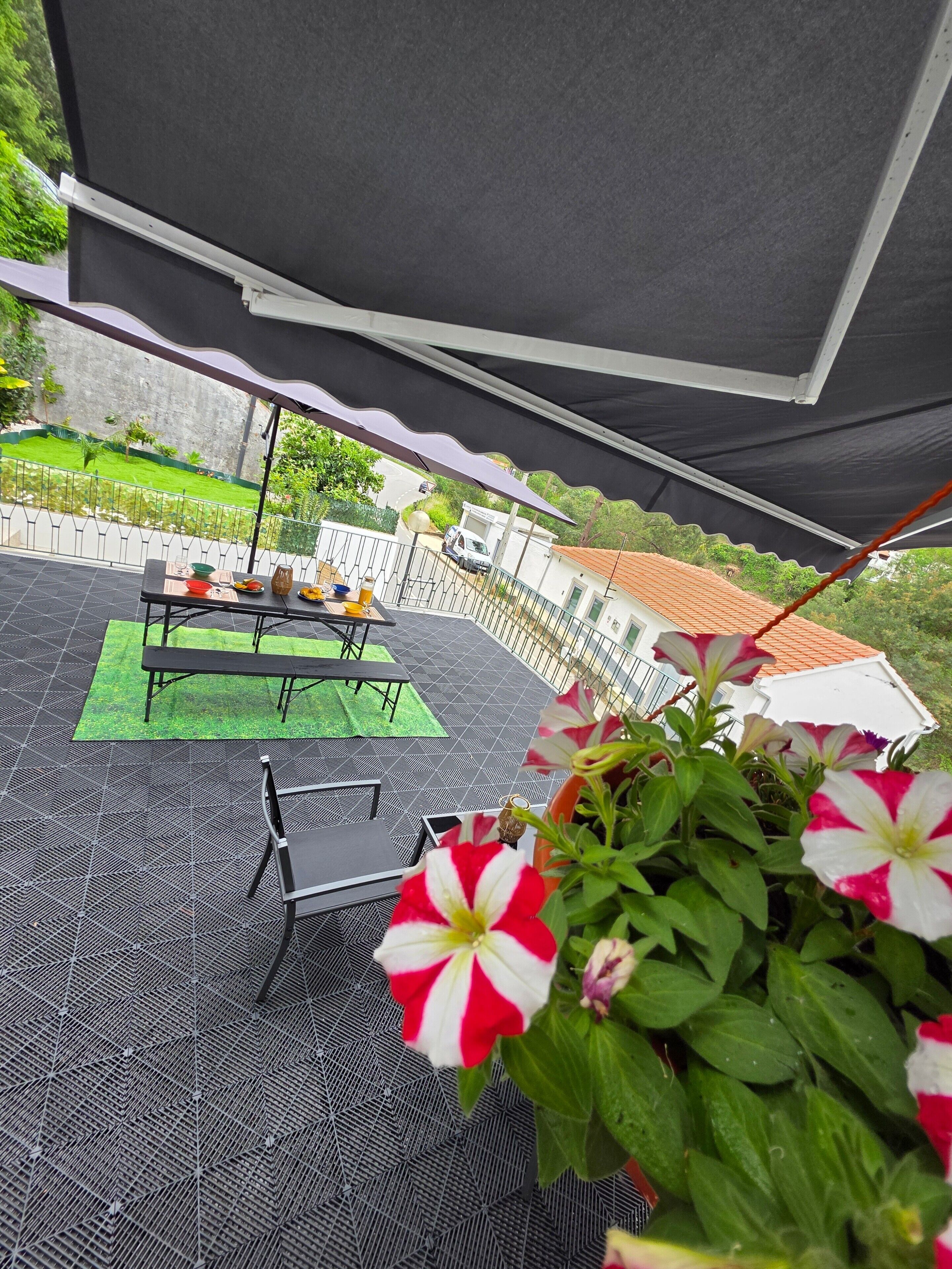 Une terrasse extérieure avec une table, des chaises et un espace vert.