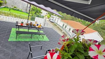 Une terrasse extérieure avec une table, des chaises et un espace vert.