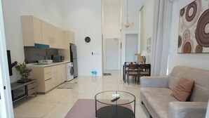 Een moderne woonkamer met een glazen salontafel, een bank en een eetgedeelte met stoelen.