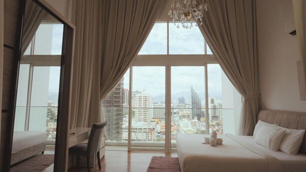 Een hotelkamer met een groot raam, een bed, een stoel en een kroonluchter.