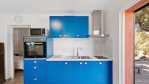 Eine kleine Küche mit blauen Schränken, einer Mikrowelle und einem Spülbecken.