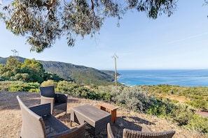 Mobiliario de mimbre para exteriores, una mesa de madera y vistas a la costa.