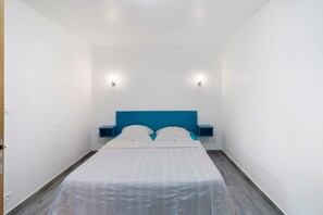 Une chambre à coucher avec un lit, deux tables de chevet et des lampes fixées au mur.