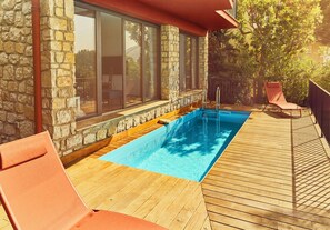 A swimming pool with a wooden deck, stone walls, and a glass-enclosed room. - Wonderfull view! (Èze)