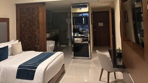 Ein Hotelzimmer mit Bett, Schreibtisch, Stuhl, Badezimmer und einer Minibar.