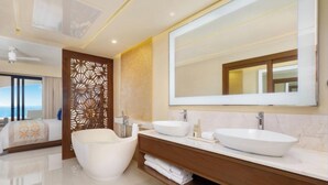 Ein modernes Badezimmer mit großem Spiegel, zwei Waschbecken, einer Badewanne und Meerblick.