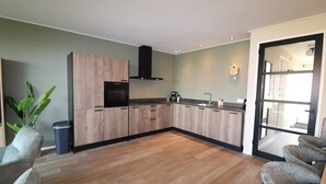 Een moderne keuken met houten kastjes, een zwarte afzuigkap en een groot raam.