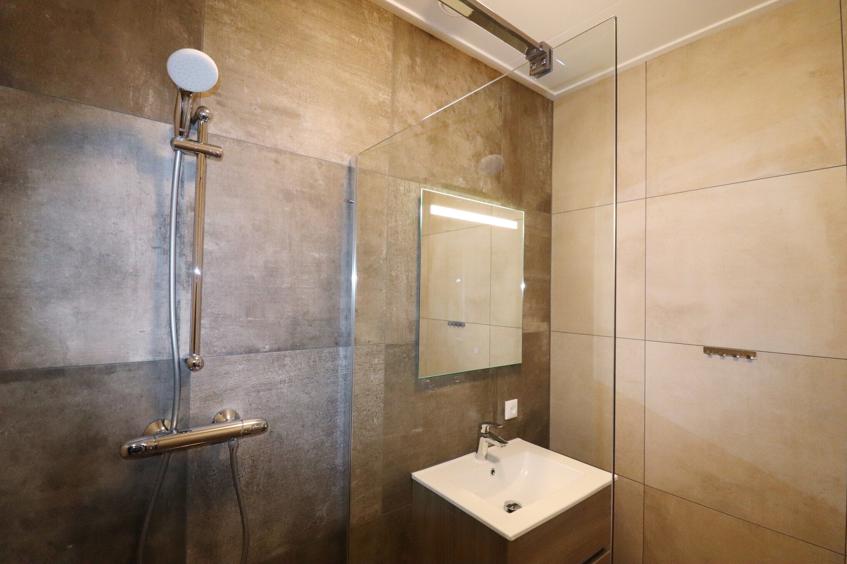 Un bagno con doccia, lavandino e specchio.