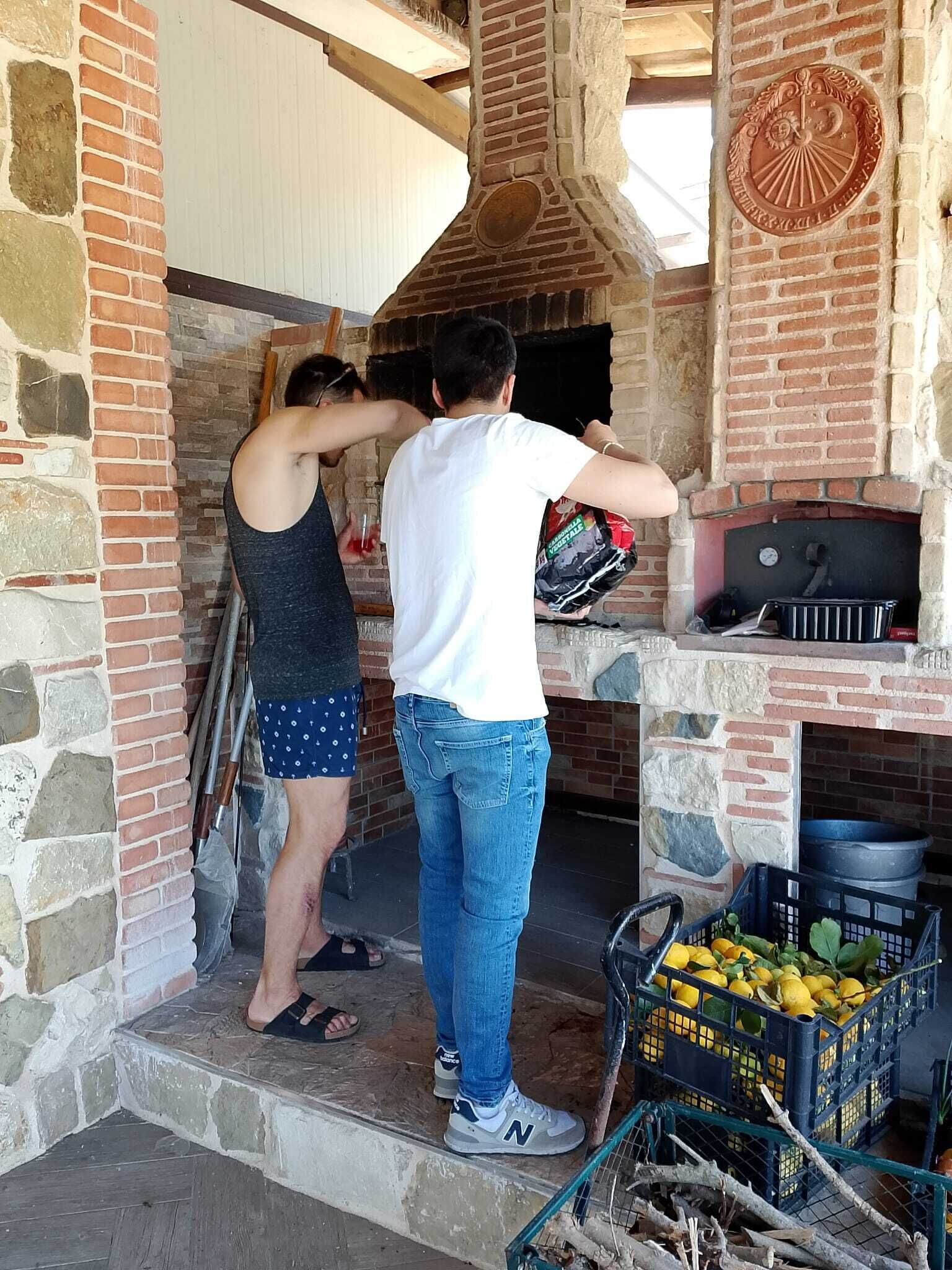 Un horno de ladrillo con una chimenea, un muro de piedra y una cesta de limones.