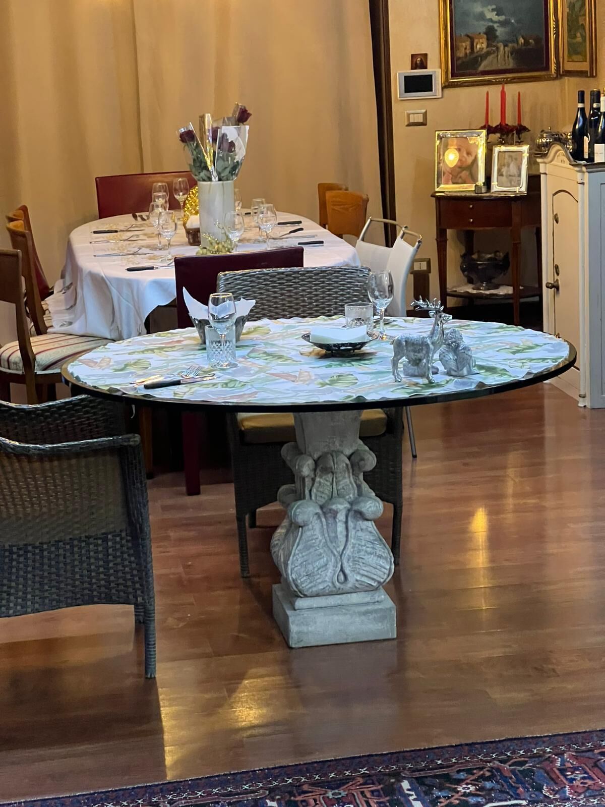 Un coin repas avec une table ronde dressée pour deux personnes, entourée de chaises en osier.