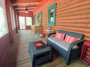 A log cabin with a covered porch, a sofa, a small table, and a dog bed. - Cozy Cabin w King, 8-Stall Barn/Borders Big South Fork Natl Park, Pet-Friendly (Oneida)
