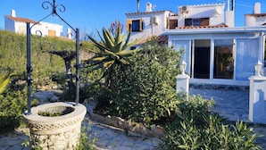 Un bâtiment blanc avec un toit en tuiles, un chemin de pierre et une grande plante d’aloe vera.