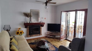 Un salon avec une cheminée, un téléviseur et un ventilateur de plafond.