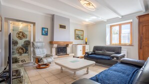 Un salon avec une cheminée, un canapé en cuir, un fauteuil et une table basse en verre.