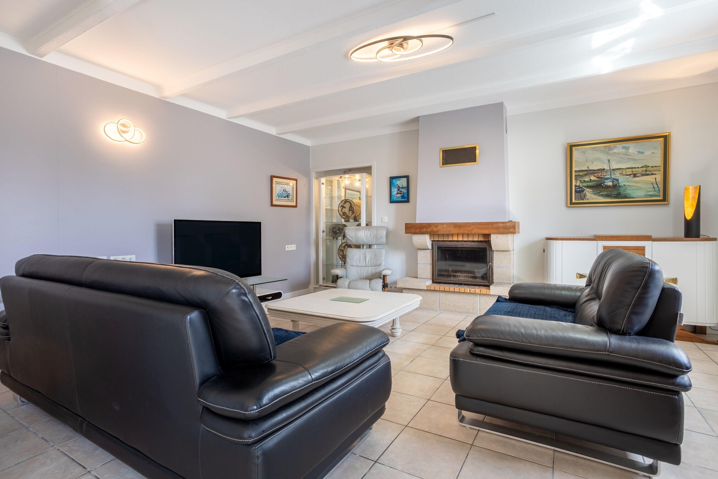 A living room with a fireplace, leather sofas, a flat-screen TV, and a coffee table.