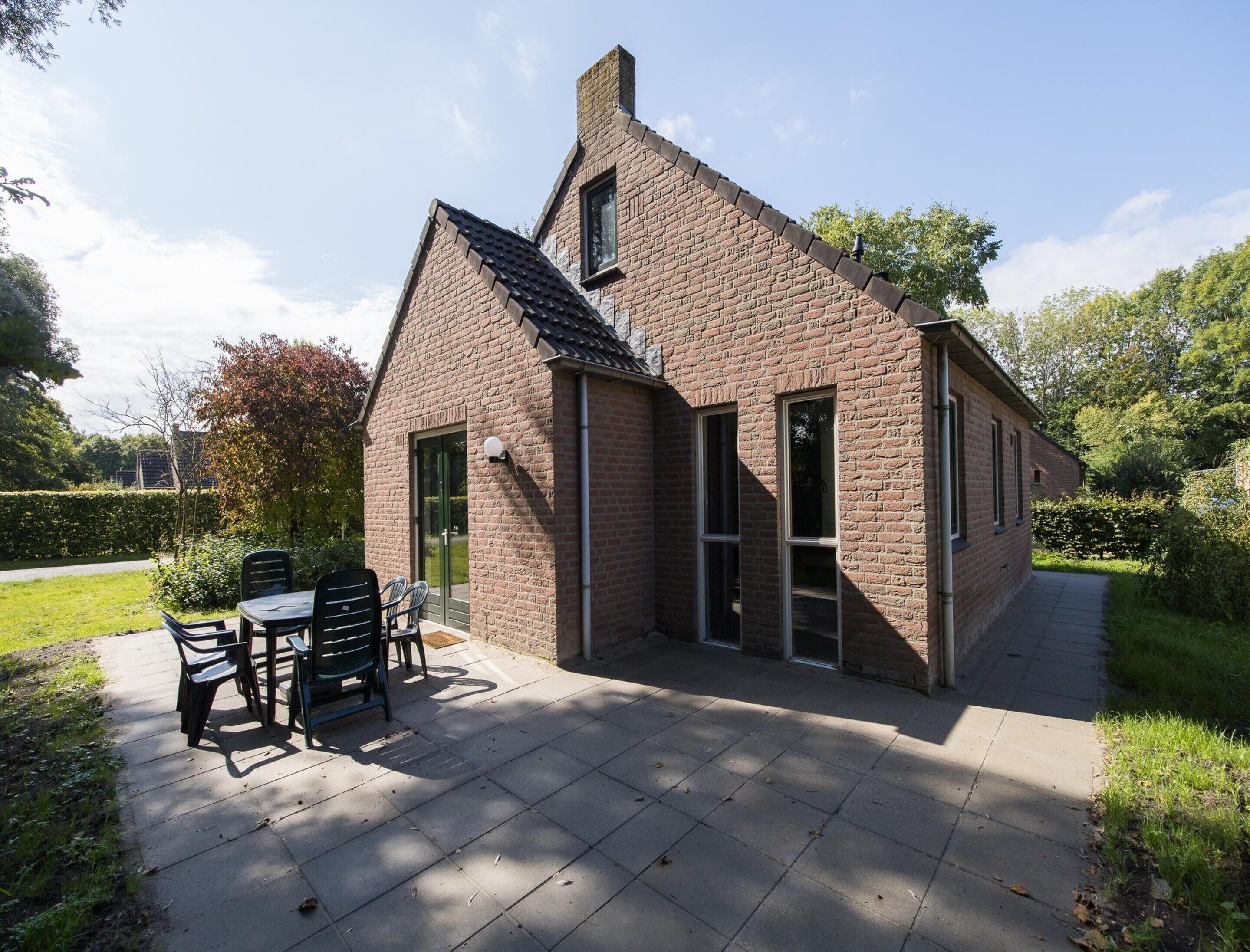 A brick house with a patio, a table, and chairs.