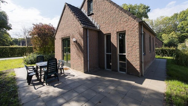 A brick house with a patio, a table, and chairs. - 5-guest Forest Bungalow in Ewijk (Ewijk)