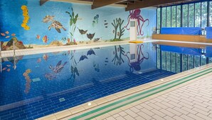 An indoor swimming pool with a mural of marine life, a diving board, and a clear view of the outside. - 5-guest Forest Bungalow in Ewijk (Ewijk)
