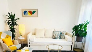 Uma sala de estar com sofá, poltrona, mesinha de centro, abajur e planta.