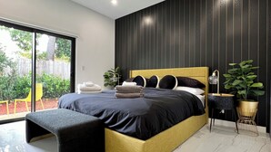A modern bedroom with a large bed, a bench, a small table, and a potted plant. - Stylish comfortable villa. (Fort Lauderdale)