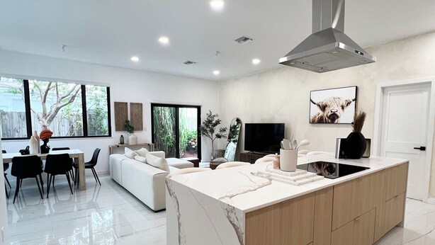 A modern kitchen with a central island, recessed ceiling lights, and a large window providing natural light. - Stylish comfortable villa. (Fort Lauderdale)