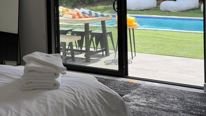 A bedroom with a bed, a bathroom mirror, and a sliding glass door leading to a pool area. - Stylish comfortable villa. (Fort Lauderdale)