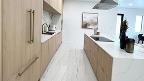 A modern kitchen with wooden cabinets, a marble countertop, and a central island. - Stylish comfortable villa. (Fort Lauderdale)