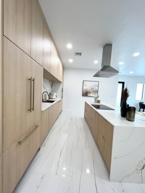 A modern kitchen with wooden cabinets, a marble countertop, and a central island. - Stylish comfortable villa. (Fort Lauderdale)