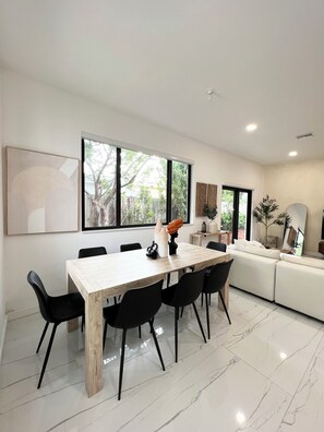 A modern dining area with a wooden table, black chairs, and a large window. - Stylish comfortable villa. (Fort Lauderdale)