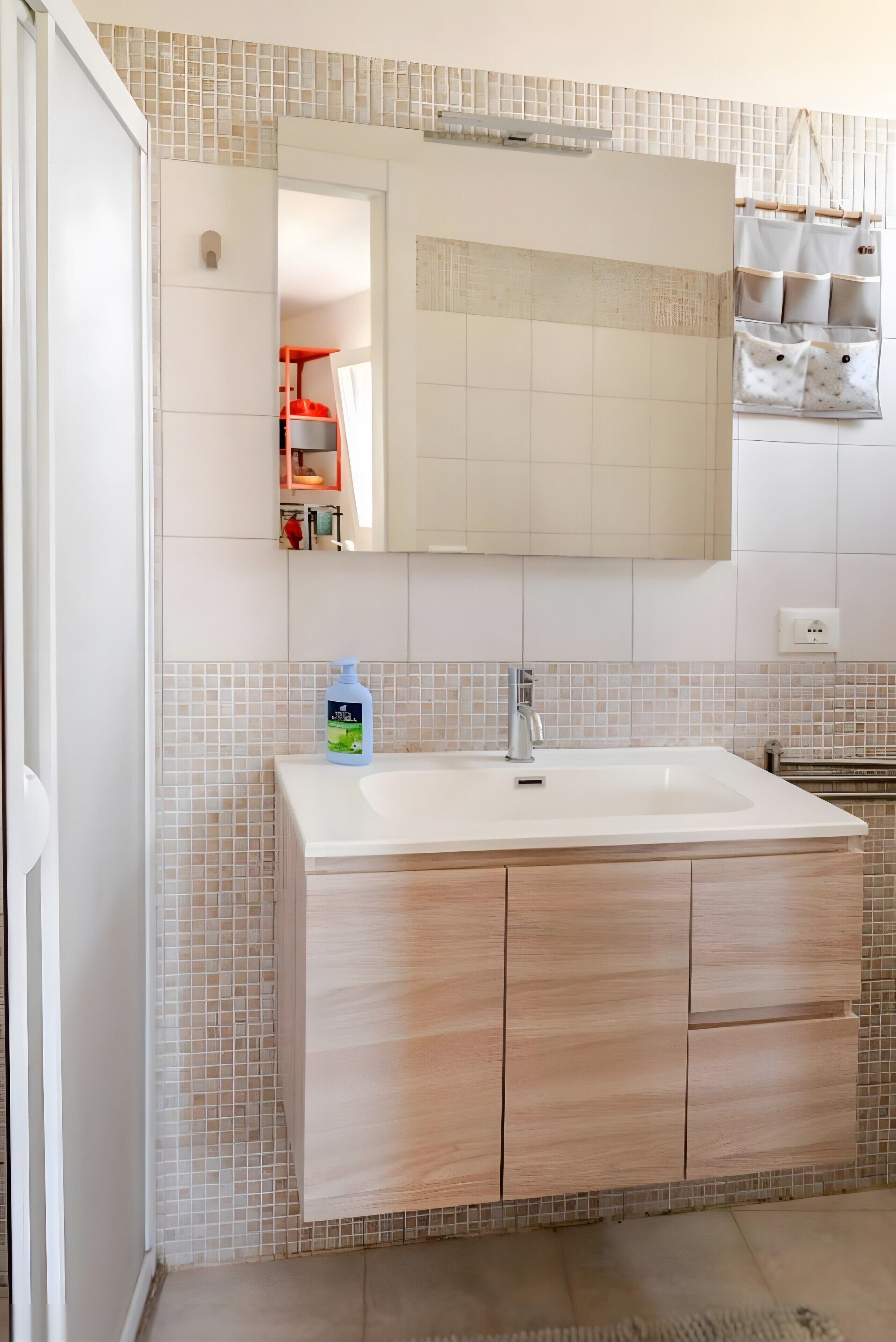 Un baño con un espejo grande, un lavabo blanco y una salpicadura de azulejos.