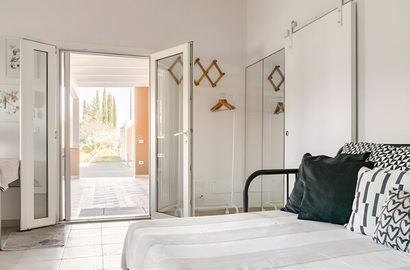 Un dormitorio con cama, armario y puerta corrediza de vidrio que da a un espacio exterior.
