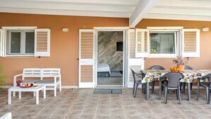 A patio area with a white bench, a table with chairs, and a door leading to an interior space. - Ruralholidays Experience in the Heart of Salento (Castri di Lecce)