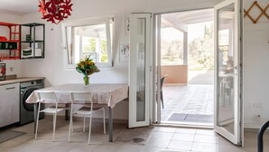 A kitchen with a table and chairs, a washing machine, and a dining area with a view to the outside. - Ruralholidays Experience in the Heart of Salento (Castri di Lecce)
