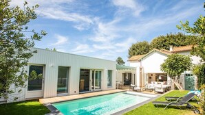 Et moderne hus med swimmingpool, en patio med liggestole og en have.