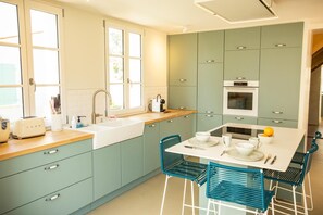 A modern kitchen with teal cabinets, a white countertop, a sink, and a dining area with blue chairs. - House 1900 Saint-Palais-Sur-Mer near sea with swimming pool and outbuilding (Saint-Palais-sur-Mer)