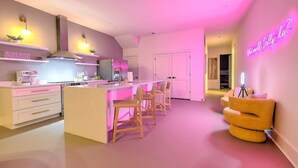 A modern kitchen with a central island, bar stools, and a neon sign. - Walk to Broadway • 14 Beds • Pool/Hot Tub • Sauna! (Nashville)