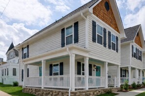 Une maison à deux étages avec un porche, des fondations en pierre et une cheminée.