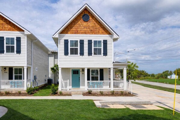 A two-story house with a porch, a front door, and a small front yard.