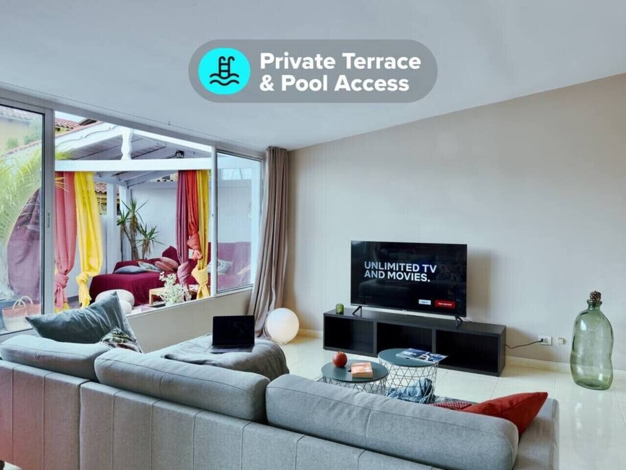 Ein modernes Wohnzimmer mit großem Fernseher, grauen Sofas und einem Schild für eine private Terrasse.