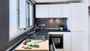 Eine moderne Küche mit einem großen Fenster, einer Spüle, einem Herd und weißen Schränken.