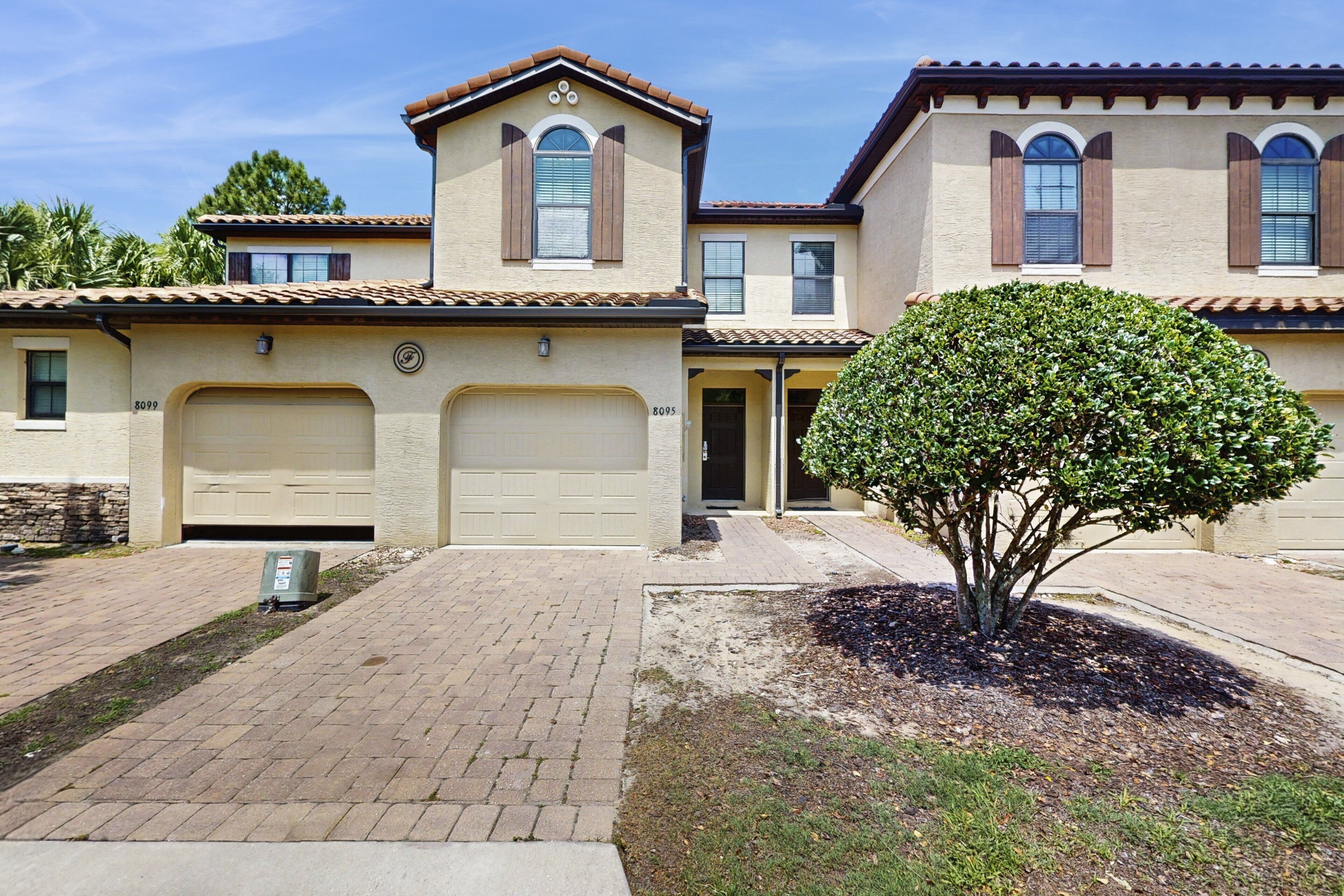 A two-story house with a garage, a driveway, and a well-maintained lawn with a large tree.