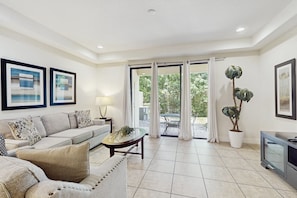 A living room with a sofa, coffee table, TV, and potted plants. - Gorgeous Snowbird-friendly Home With Pool, hot Tub, & gym - Close to Theme Parks (Davenport)