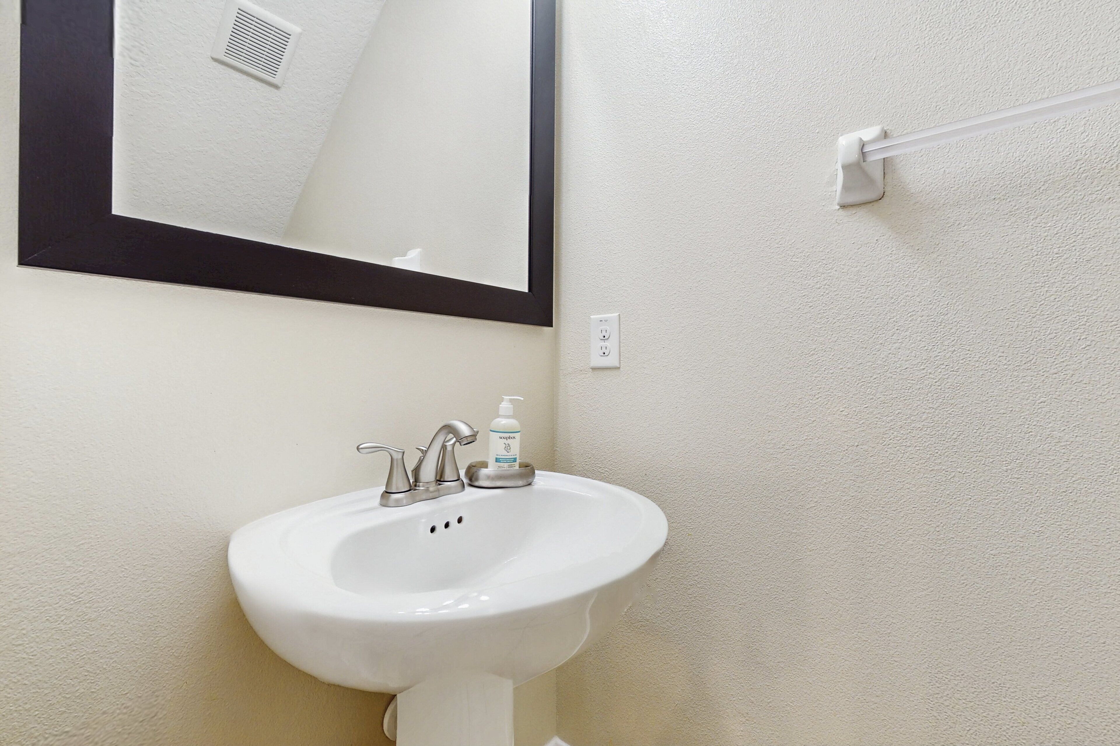 A bathroom with a white sink, a mirror, and a hand dryer.