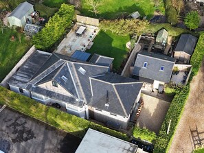 An aerial view of a residential area with multiple houses, including a large house with a sloped roof and a smaller house with a flat roof. - Le Petit Glen (Lyme Regis)