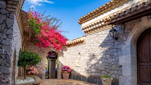 A stone building with a tiled roof, a wooden door, and a statue. - Villa Nerissa - Letojanni (Letojanni)