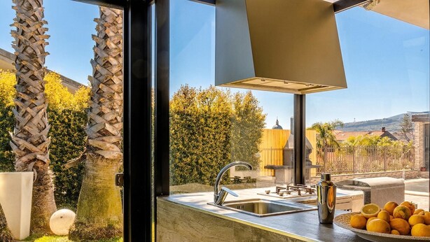 Una cucina con un lavandino, un piatto d'arance e vista sull'esterno.