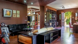 Un interno moderno con un divano nero, un tavolino, una libreria e un'area pranzo con sedie.