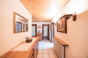 A hallway with a wooden bench, a radiator, and framed artwork on the walls. - Gîte in Southern Alsace Largue – Peaceful Countryside Retreat (Wolfersdorf)